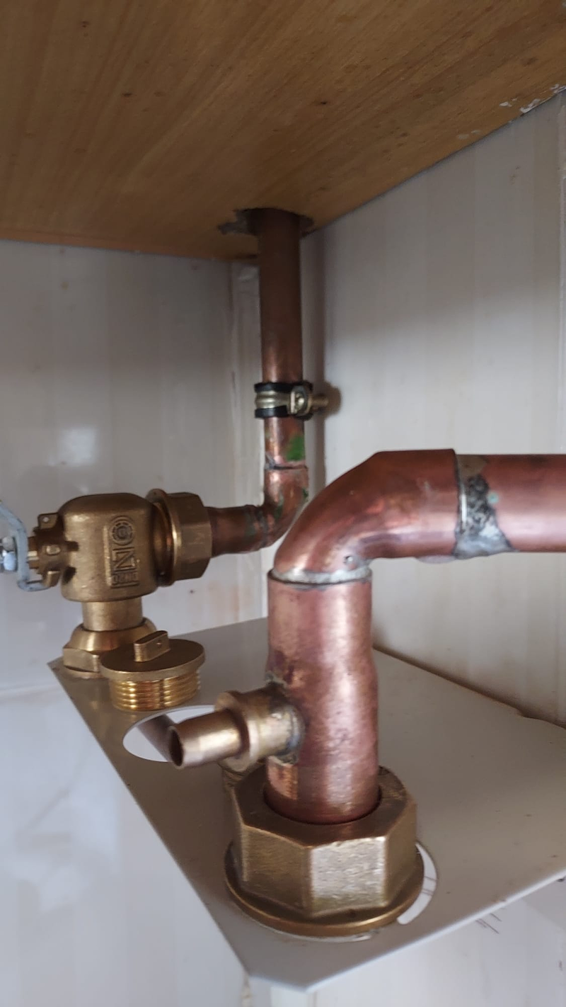 Toma de gas de cobre con su llave de corte bajo la encimera de una cocina, con las soldaduras a la vista.